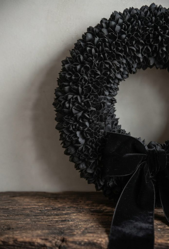 Ein großer, tiefschwarzer Türkranz aus natürlichen Bakuli-Kapseln mit einer eleganten Samtschleife, präsentiert als DIY-Inspiration auf benbino.